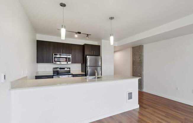 A modern kitchen with a white countertop and stainless steel appliances.