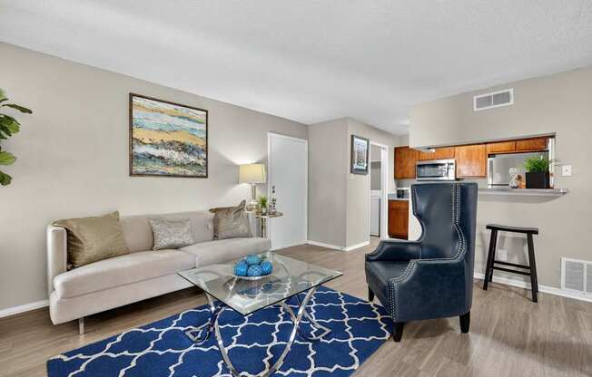 A living room with a white couch, a blue chair, and a painting on the wall.