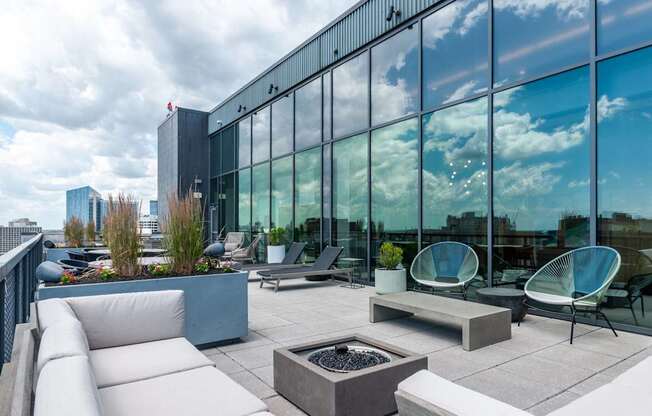 A modern outdoor seating area with white furniture and a fire pit.