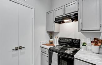 a kitchen with white cabinets and a black stove