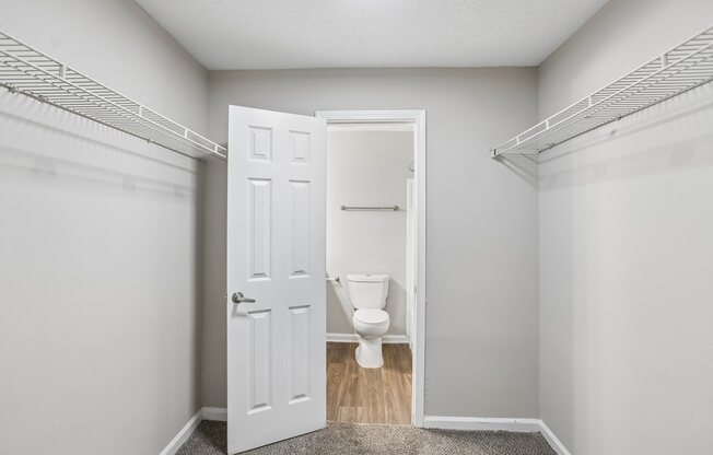 A white door is open to a bathroom with a toilet.