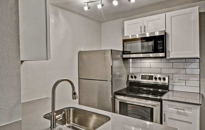 a kitchen with white cabinets and stainless steel appliances