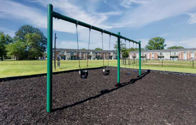 an empty swing set in a playground in a park