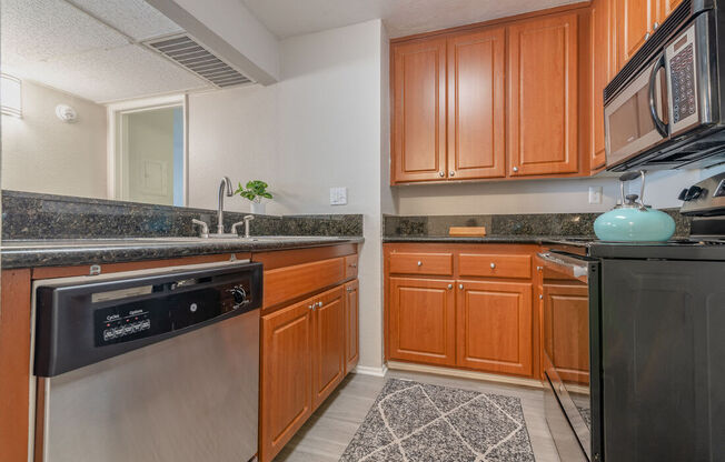 a kitchen with stainless steel appliances and wooden cabinets at City View Apartments at Warner Center, Woodland Hills, CA
