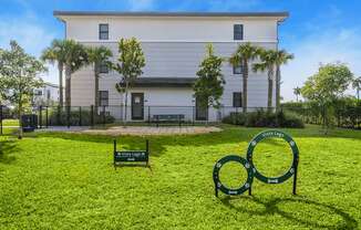 a white building with palm trees and a green lawn with a sign in the grass