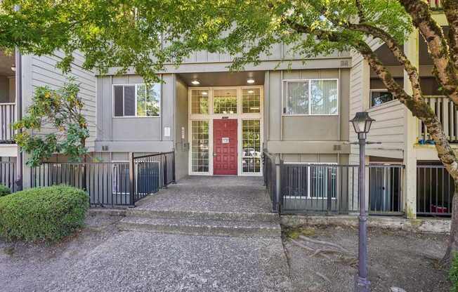 A building with a red door is surrounded by a black fence.