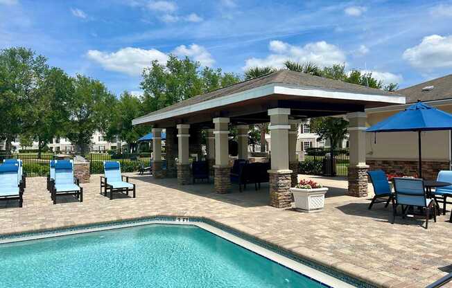 A pool with a gazebo and chairs around it.