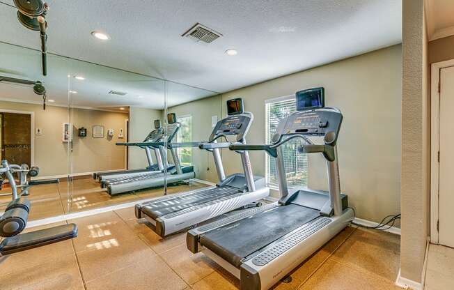 a gym with cardio equipment on the floor and mirrored walls