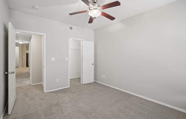 A room with a ceiling fan and carpeted floor.