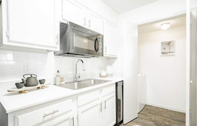 a kitchen with white cabinets and a sink and a microwave