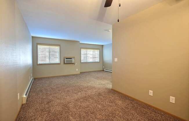 an empty living room with carpet and a window. Fargo, ND Urban Plains Apartments
