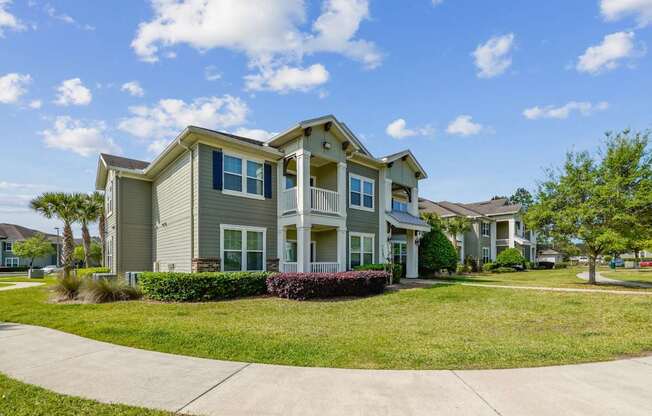 A large house with a grey roof and a green lawn in front.