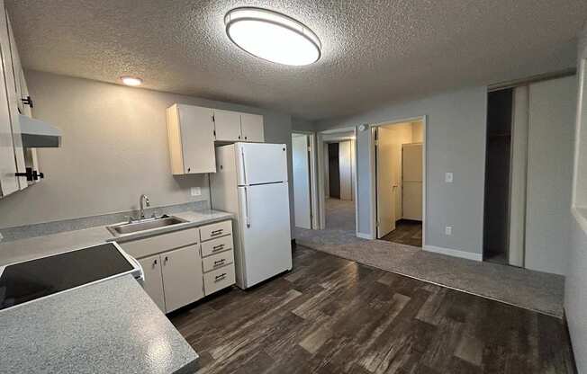 A kitchen with a white fridge, sink, and cabinets.