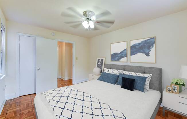 Bedroom with bed, nightstands, ceiling fan and hardwood floors at colonnade apartments in washington dc