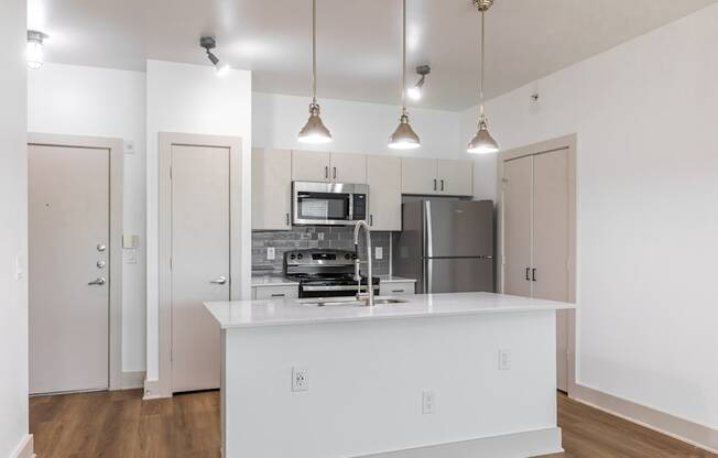 A kitchen with a white island and pendant lights.