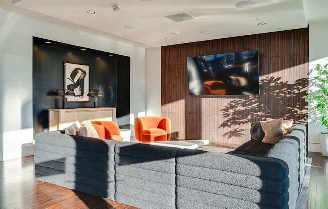 A living room with a grey couch and a television on the wall.