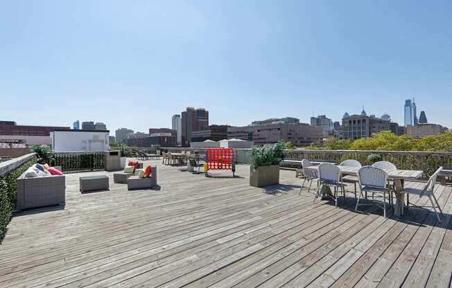 A wooden deck with chairs and tables overlooking a city skyline.