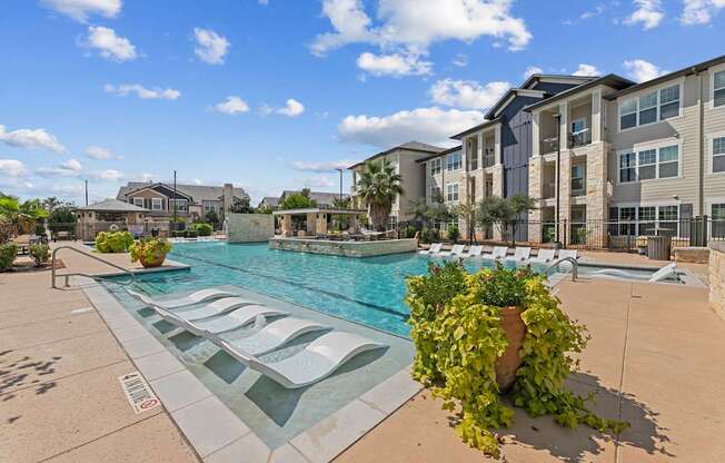 A pool surrounded by chairs and buildings.