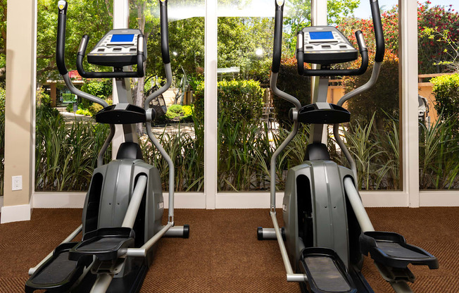 Two exercise bikes are placed in a room with a window.