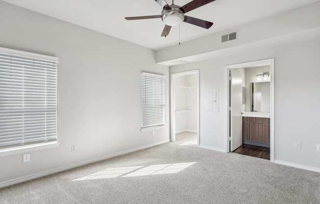 an empty living room with a ceiling fan and a door to a bathroom