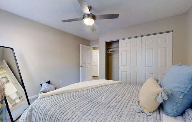 A bedroom with a bed, pillows, and a ceiling fan.
