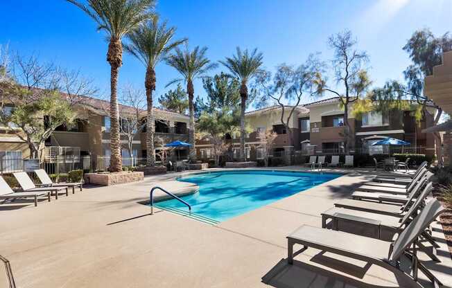 A pool surrounded by lounge chairs and palm trees. at The Fairways by Picerne Apartments, Nevada