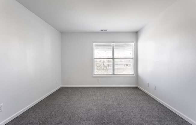 A room with a window and carpeted floor.