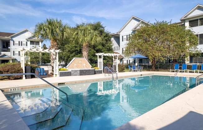 a swimming pool with blue chaise lounge chairs and palm trees in the background