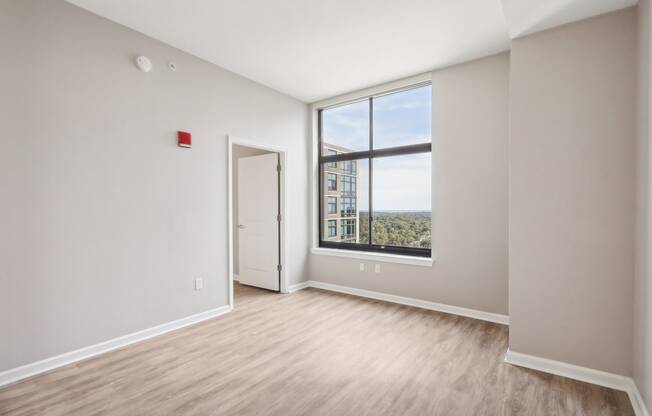 an empty living room with a large window and wood flooring