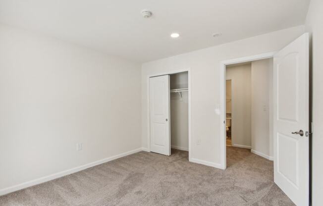 a bedroom with white walls and a door to a closet