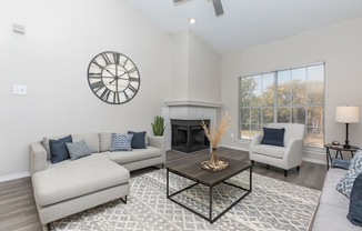 A living room with a fireplace, a couch, a chair, and a clock on the wall.