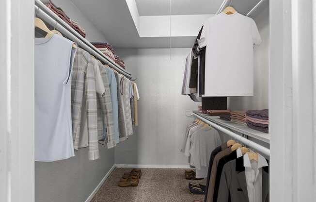 a walk in closet filled with clothes and shoes