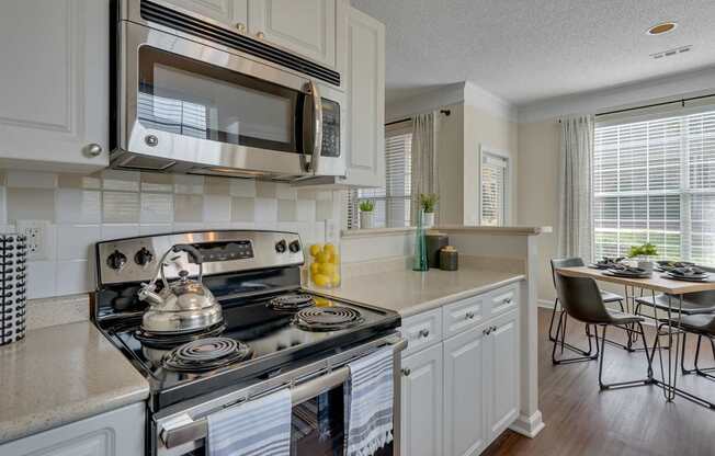 A modern kitchen with a stove, microwave, and a dining table.