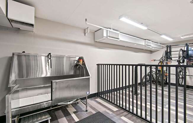 A large stainless steel sink in a room with a black fence.