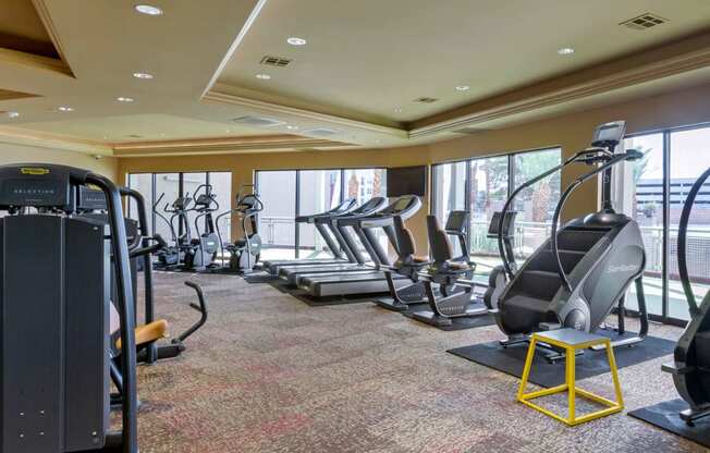 a gym with cardio equipment in a room with windows at The Rays at Vegas Towers Apartments, Las Vegas, NV 89119