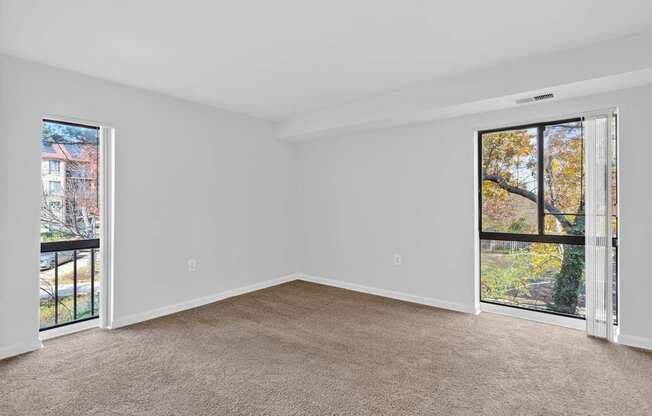 A room with a carpeted floor and two open doors leading to balconies.