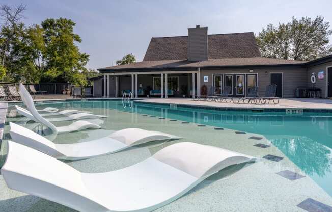 a pool with white chairs and a house in the background