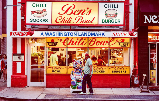 a man standing outside of a chili bowl restaurant on a city street