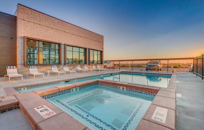 A pool with a red brick building behind it.