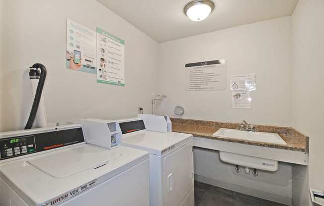 a laundry room with two washing machines and a sink