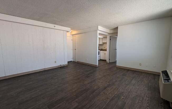 an empty living room with wood floors and white walls