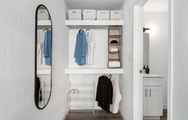 A hallway with a mirror, coat rack, and shelves.