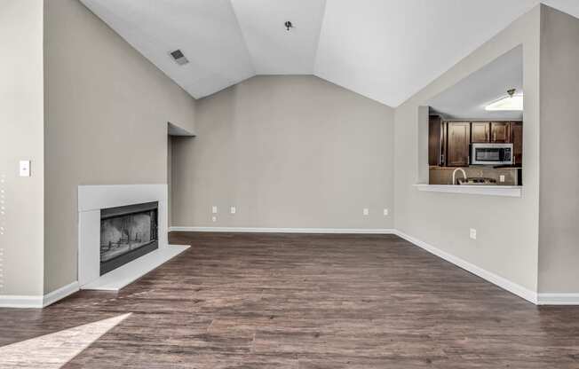 an empty living room with a fireplace and a kitchen