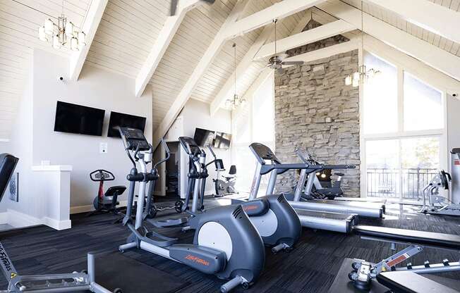 a gym with exercise machines and a stone fireplace