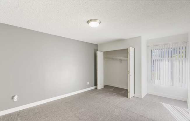 an empty bedroom with a closet and a window