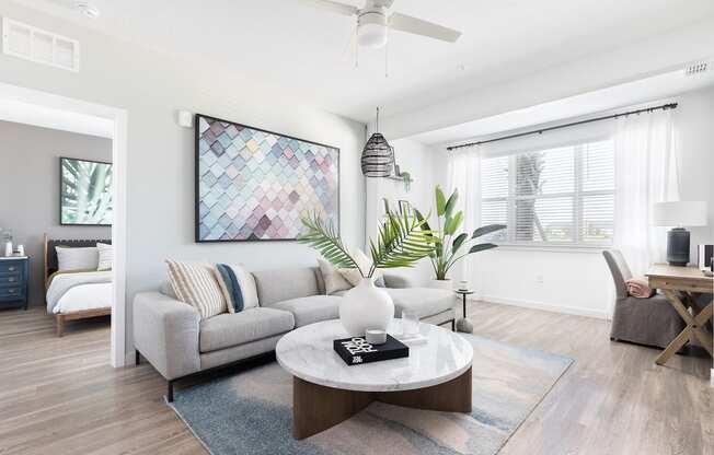 spacious living room with ceiling fan, wood-style floors, and model furnishings