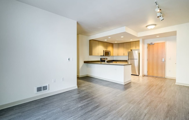 the living room and kitchen of an empty apartment with wood flooring