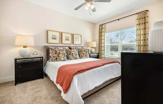 A bedroom with a bed, nightstand, and a ceiling fan.