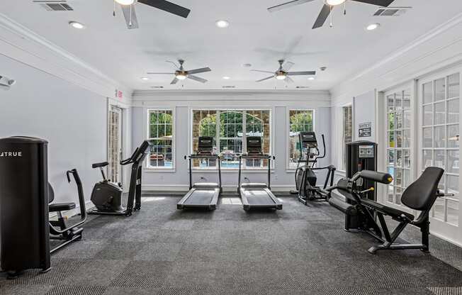 A gym with a variety of equipment including treadmills, weights, and a bench press.