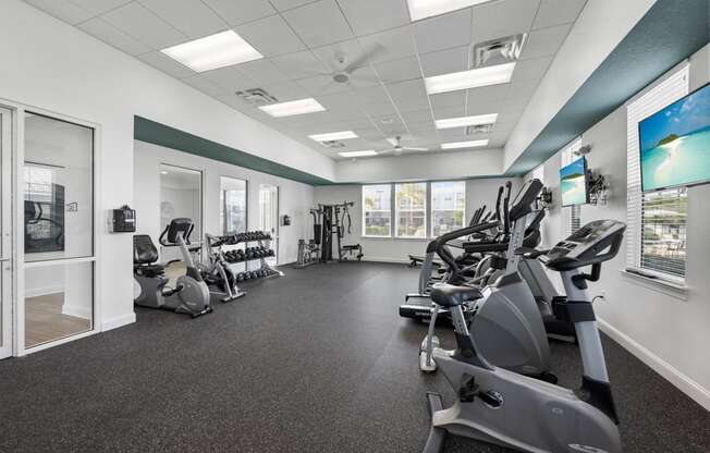 a gym with various exercise machines and a tv